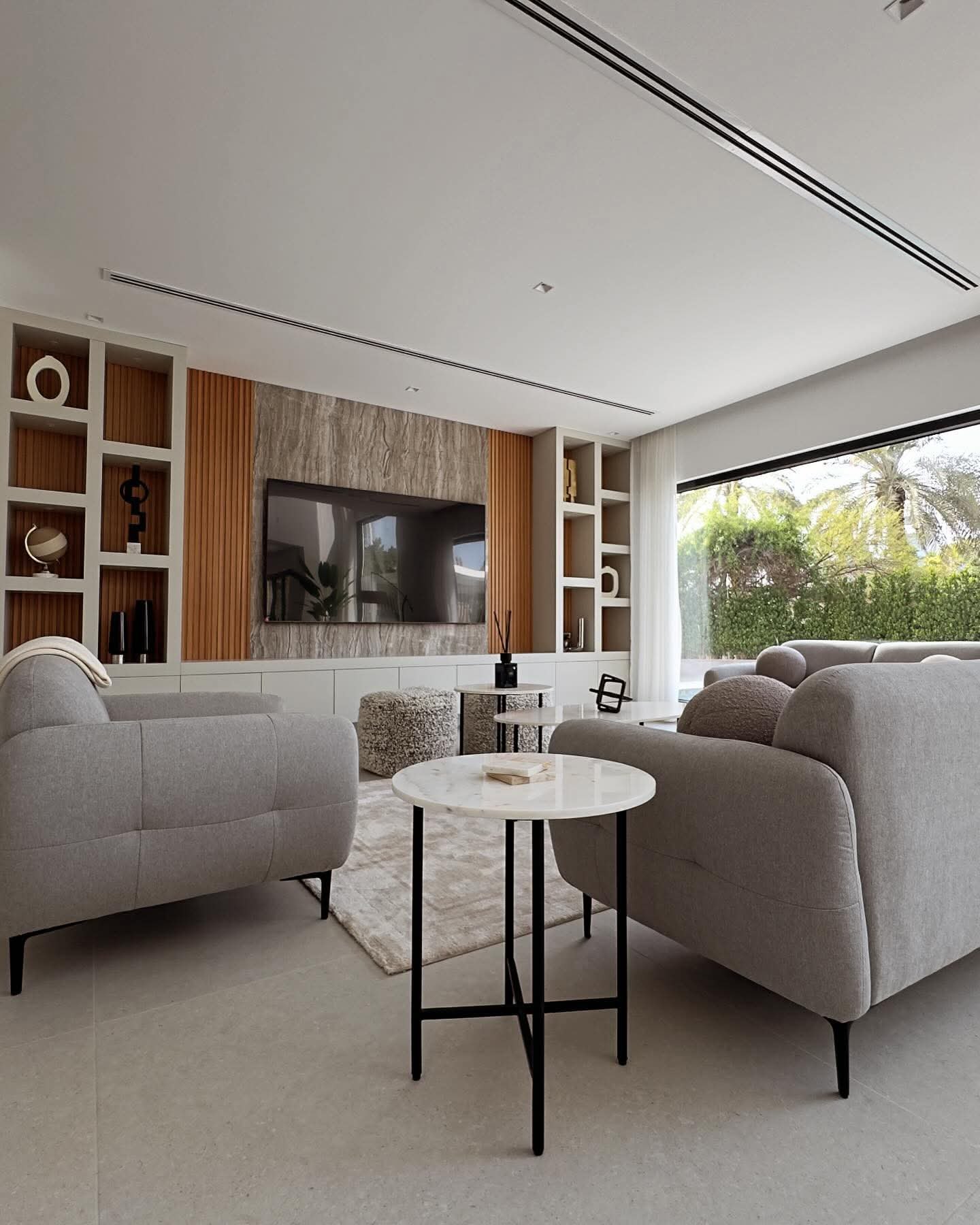 Completed villa renovation in Dubai showing an open-plan living space with bespoke joinery, media wall and garden outlook